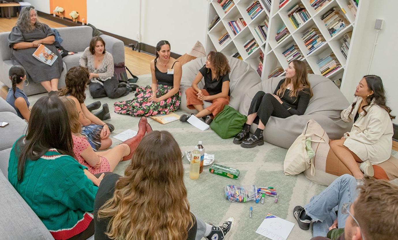 several students sit on the floor in a circle in the casa living room